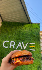 Guest holding a Crave smash burger by the storefront